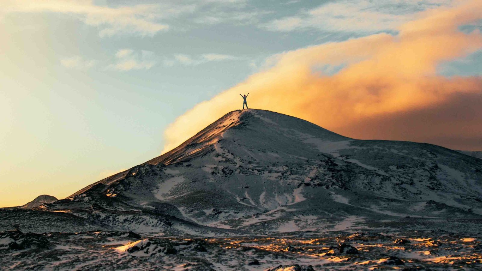 Person celebrating on a snowy mountaintop at sunrise, symbolizing breakthrough through EMDR therapy