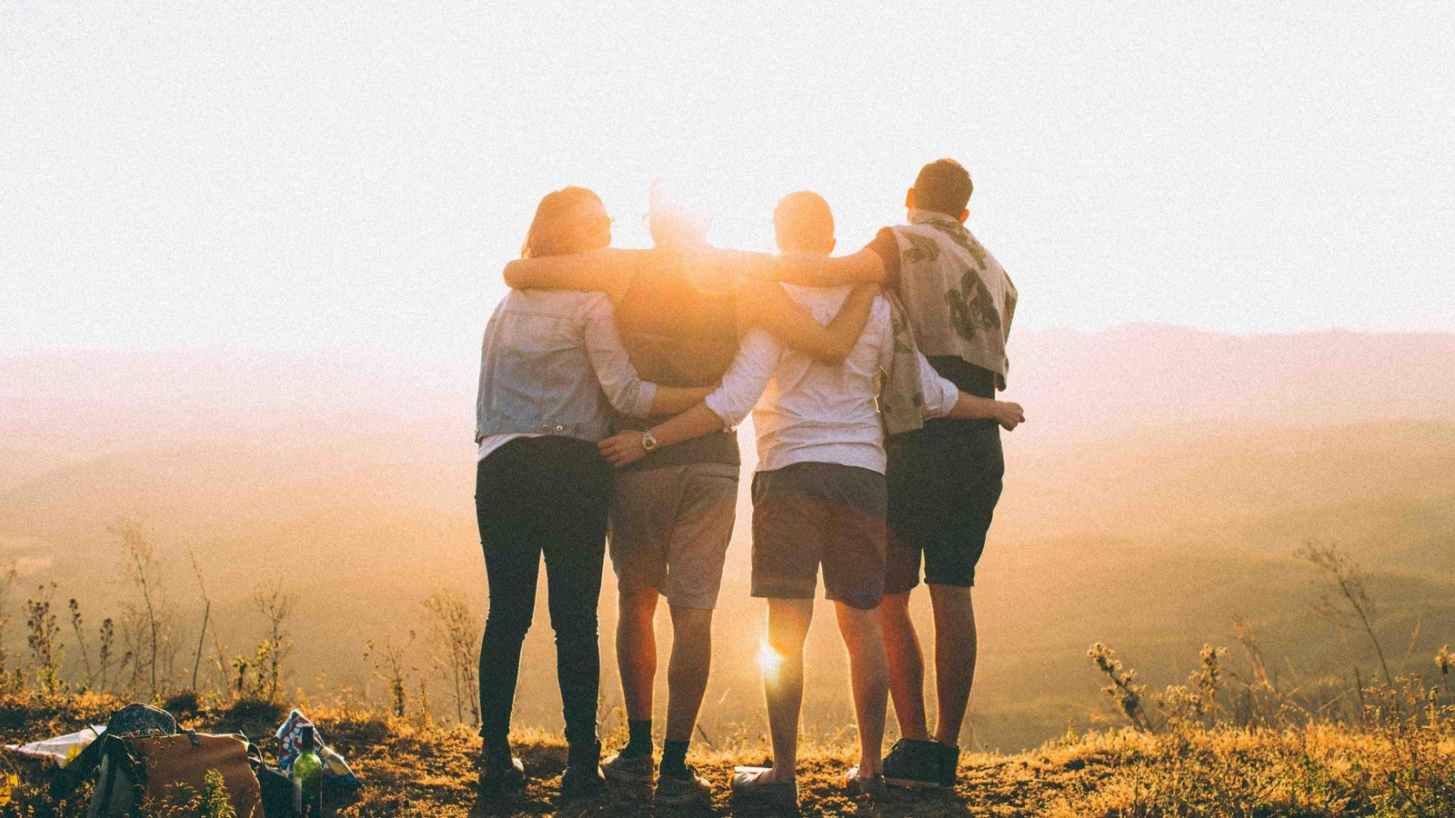Four people with arms around each other watching the sunset, symbolizing healing from trauma through connection and support